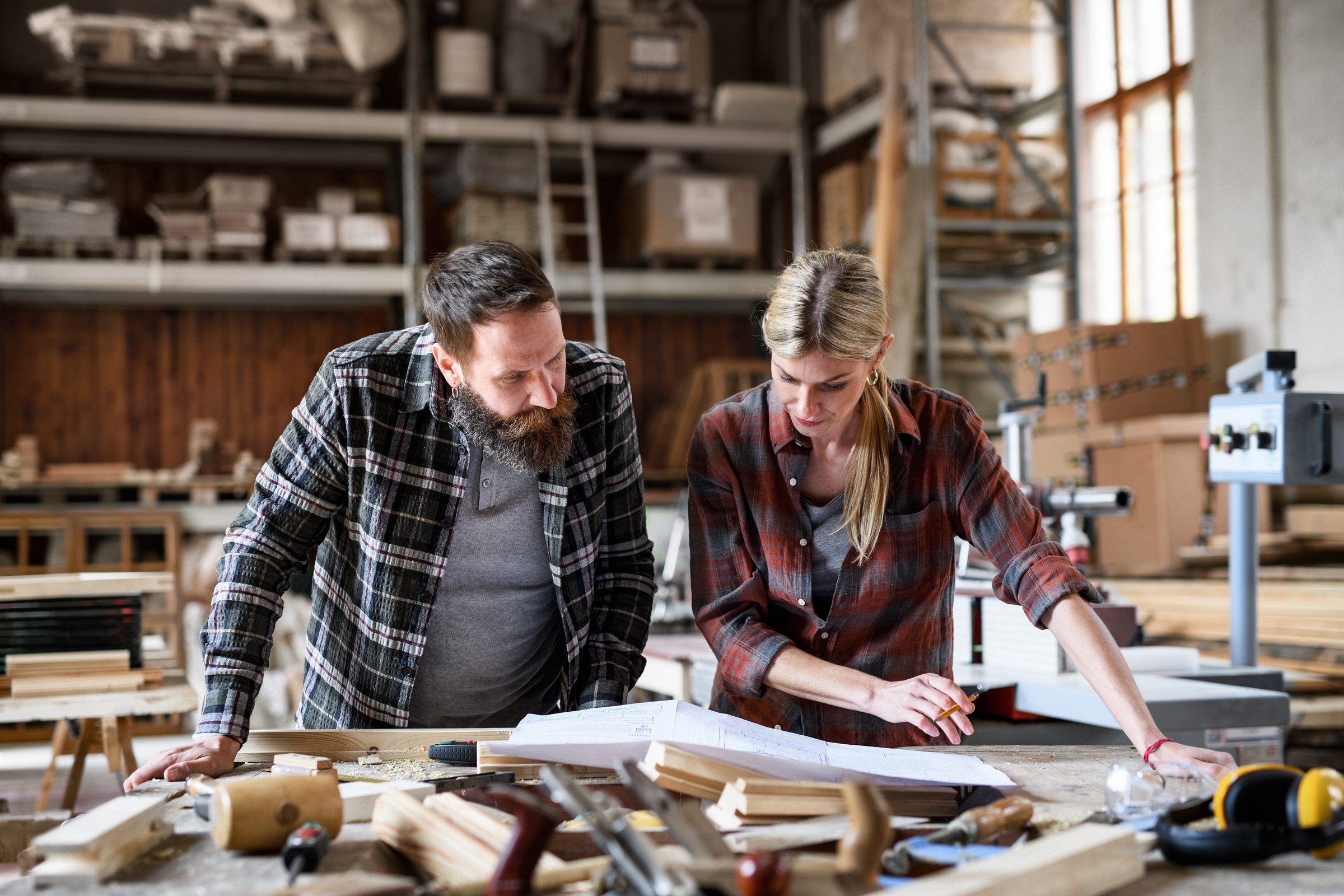 Two people reviewing plans together at a workshop bench