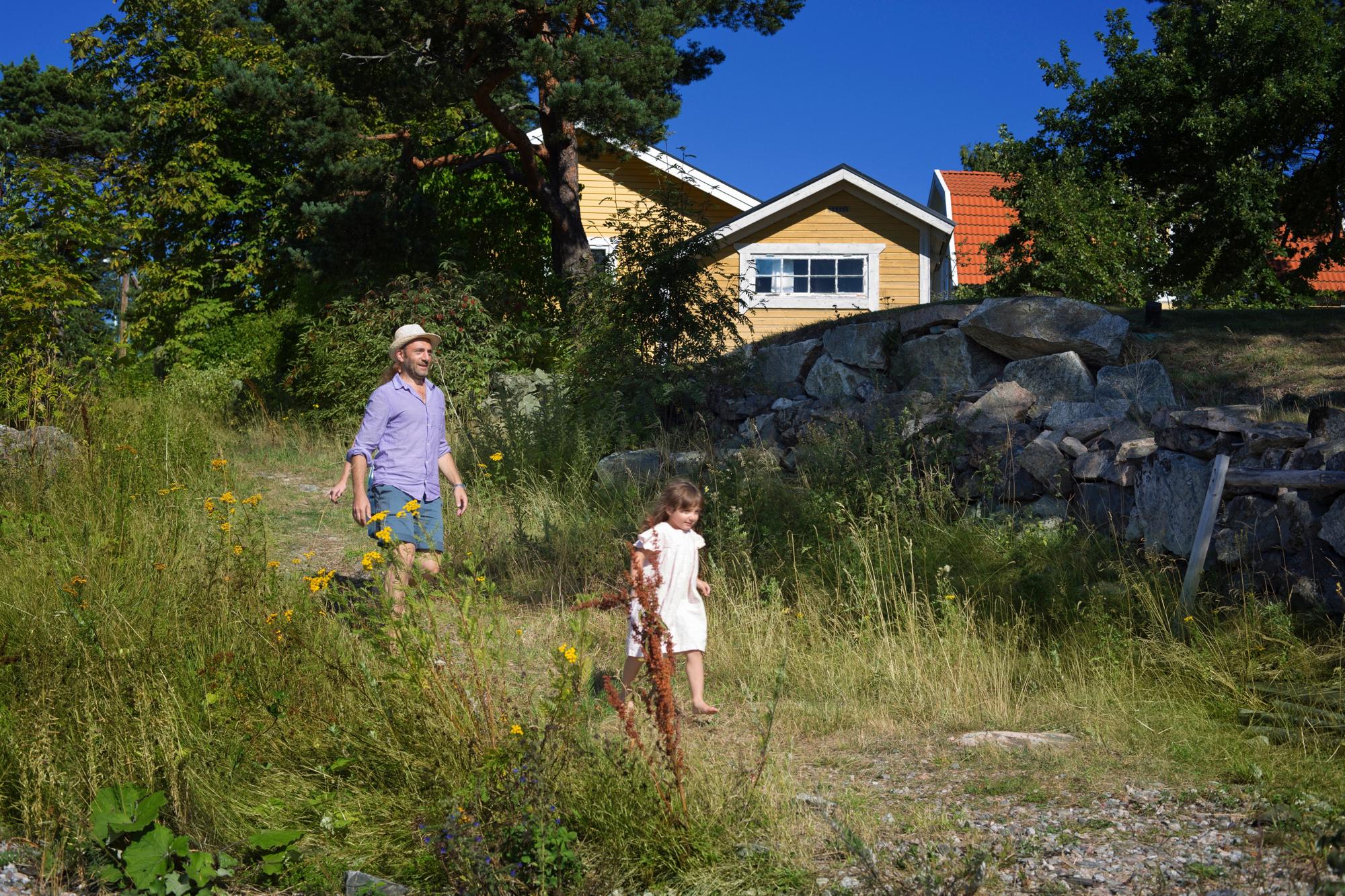 A man and a small child walking through a garden at the end of the day